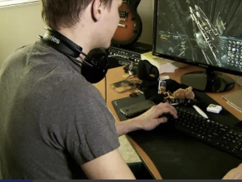 Photo of Harsh from the original persona board, seen from behind at a desk with headphones around his neck and two monitors.